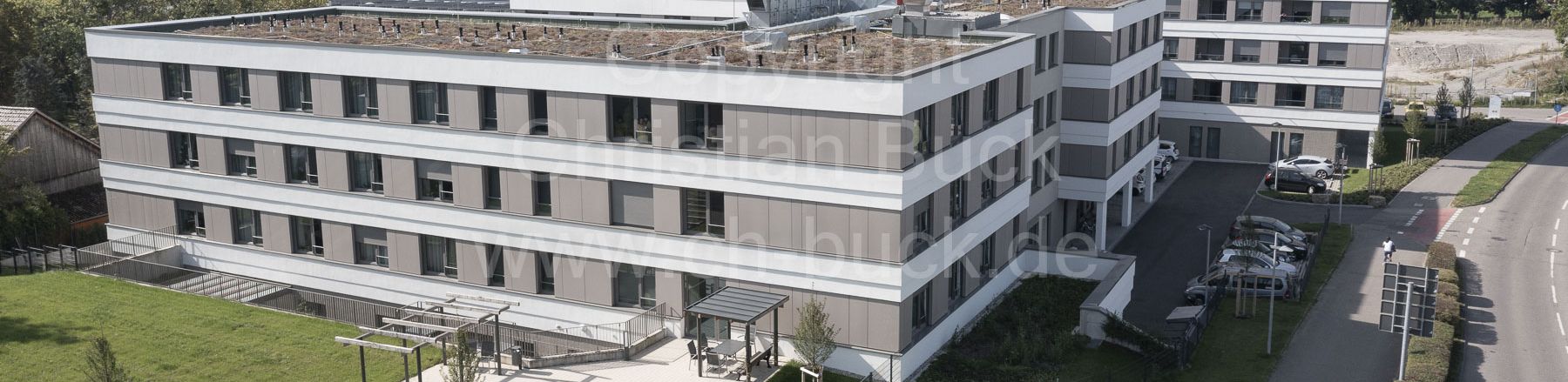 Moderner viergeschossiger Bürokomplex mit begrüntem Flachdach und Parkplatz
