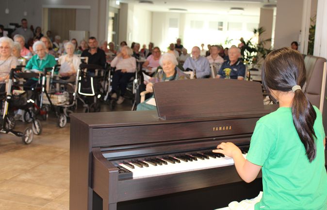 Schülerin am Klavier spielt vor Senioren beim Abendkonzert