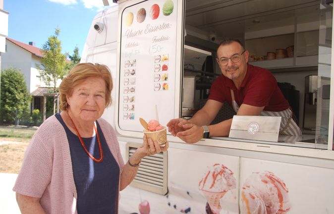 Ältere Frau erhält Eisbecher vom Verkäufer an einem Eistruck