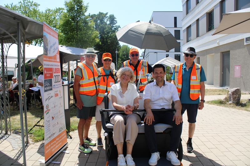 Gruppe mit Warnwesten und zwei sitzenden Gästen beim Sommerfest zum 30-jährigen Jubiläum