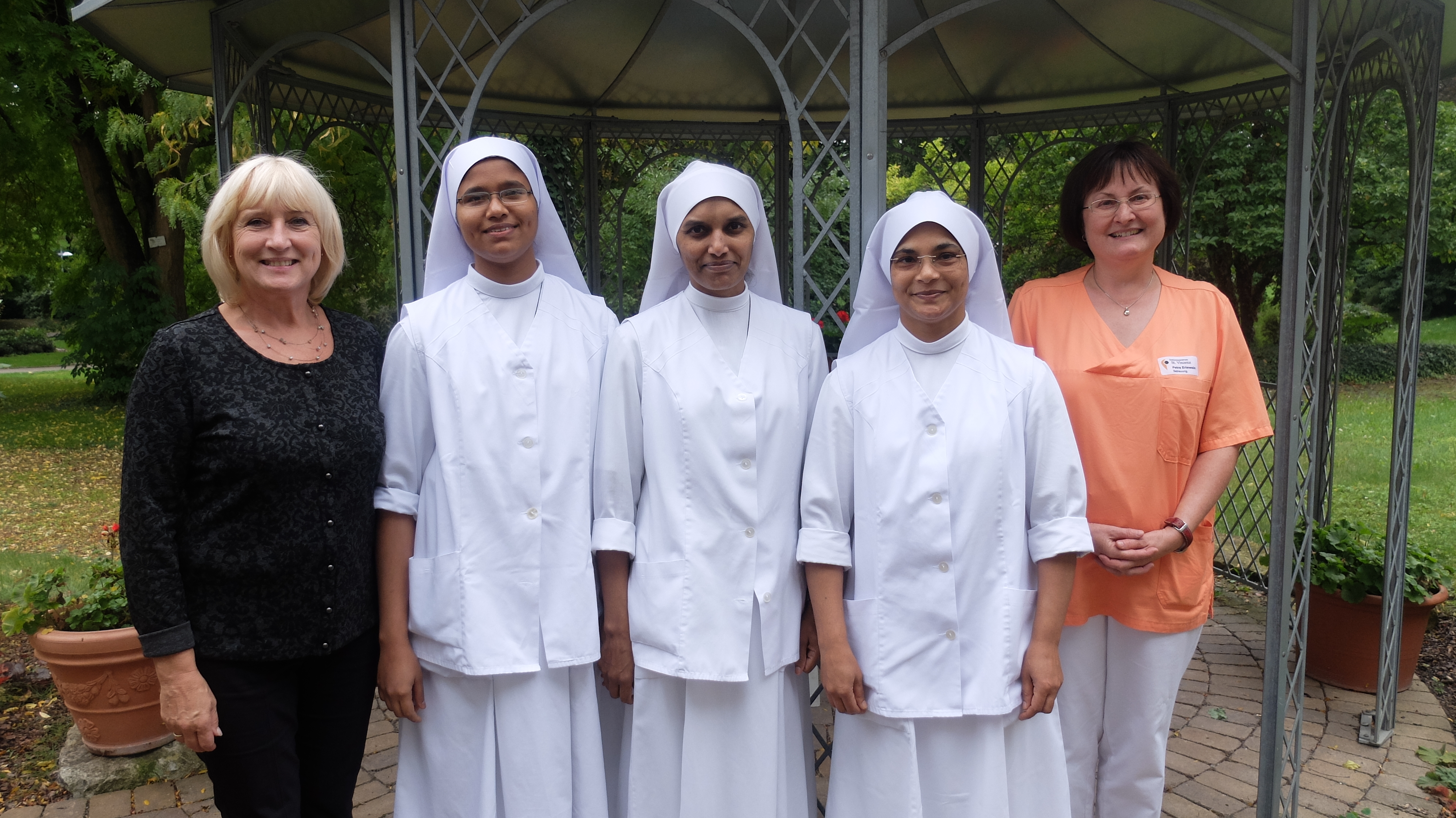 Fünf Frauen stehen nebeneinander drei tragen weiße Tuniken und Kopftücher